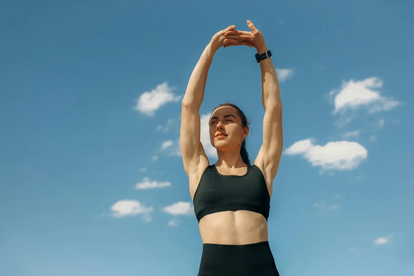 Woman stretching against a clear blue sky